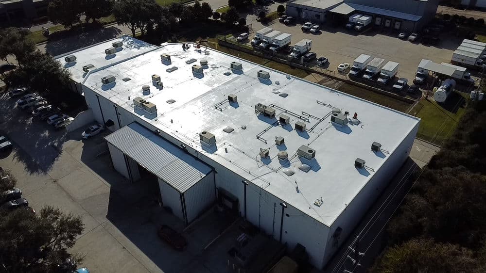 Aerial view of a commercial building with rooftop HVAC units and parking area.
